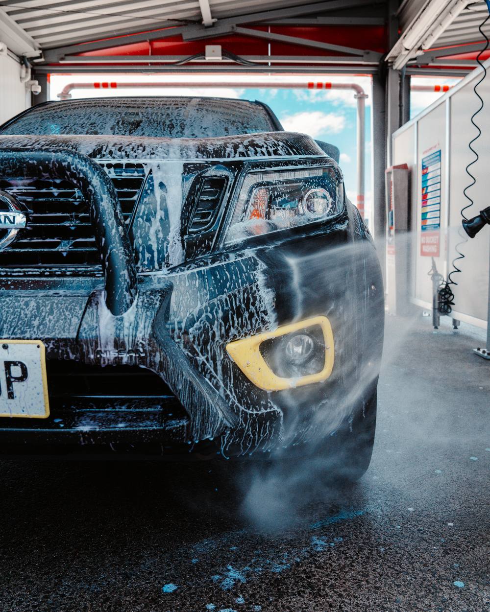 A ute covered in foam in one of the self-serve bays