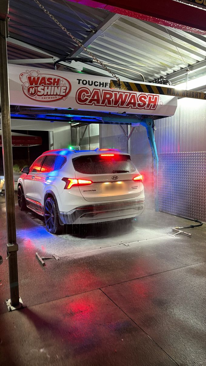 A car in the Wash N Shine touchfree wash at night